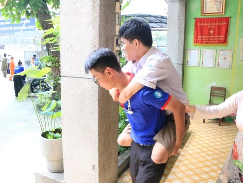 Tình nguyện viên cõng thí sinh mất tay, chân đi thi tốt nghiệp THPT 2025 - Ảnh 1.