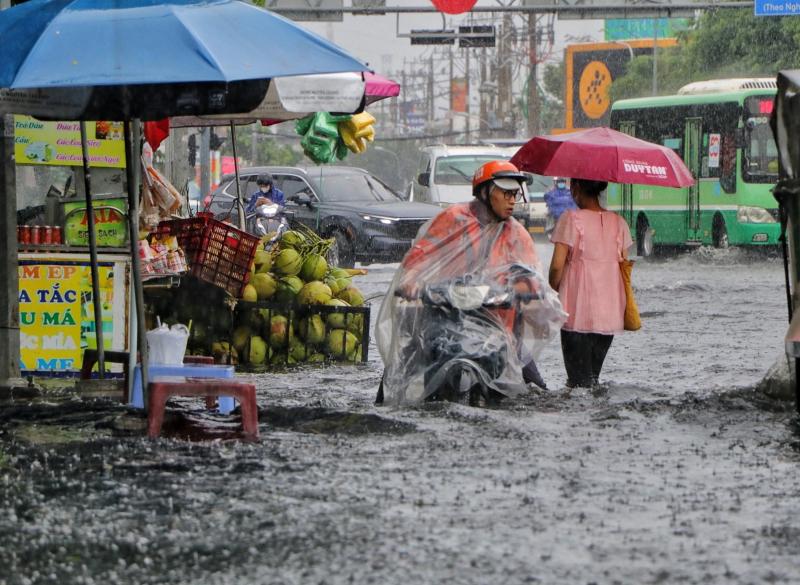 TP.HCM có mưa lớn xối xả giữa trưa: Đường ngập, người dân 'vật lộn' giữa biển nước - Ảnh 1.