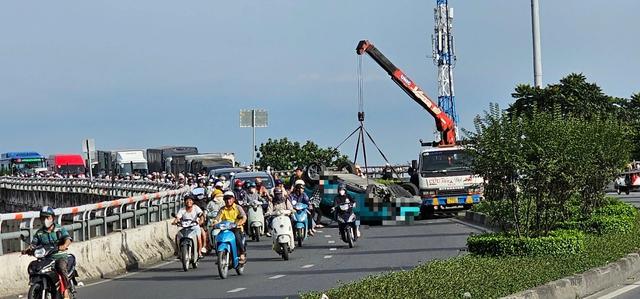 Lật xe taxi công nghệ trên cầu vượt, tài xế bị thương, ùn xe kéo dài - Ảnh 1.